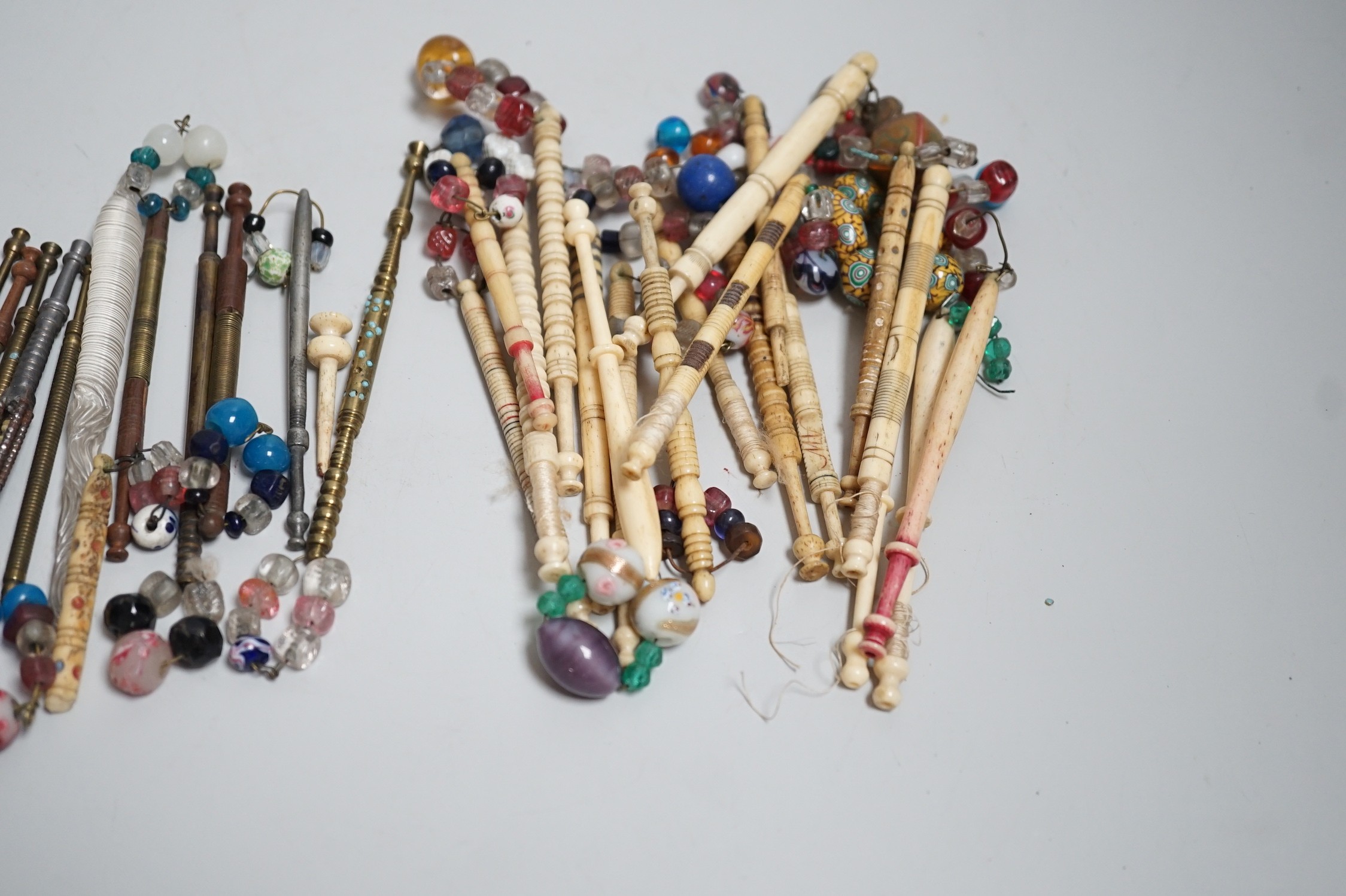 Twenty ornate 19th century turned bone and beaded topped lace bobbins and eleven ornately turned metal lace bobbins, glass bobbin and 3 broken bobbins (34)